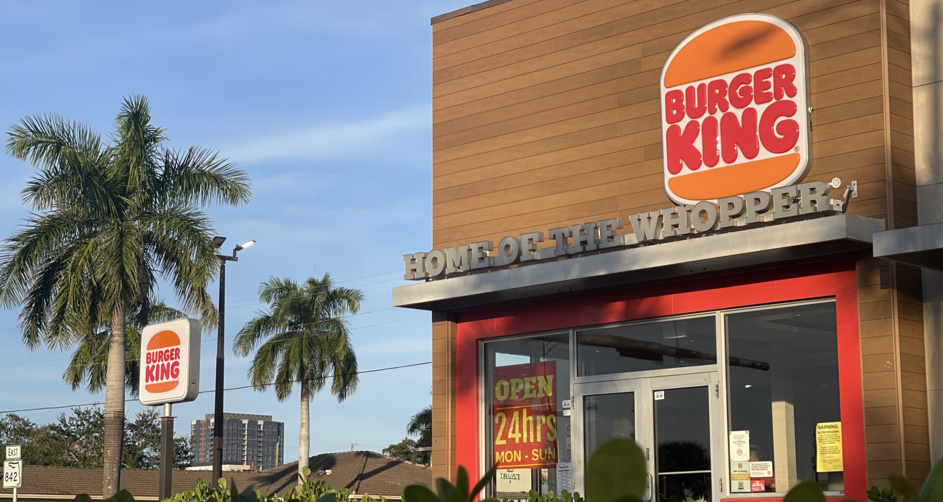 A Burger King store is surrounded by palm trees and South Florida shrubs