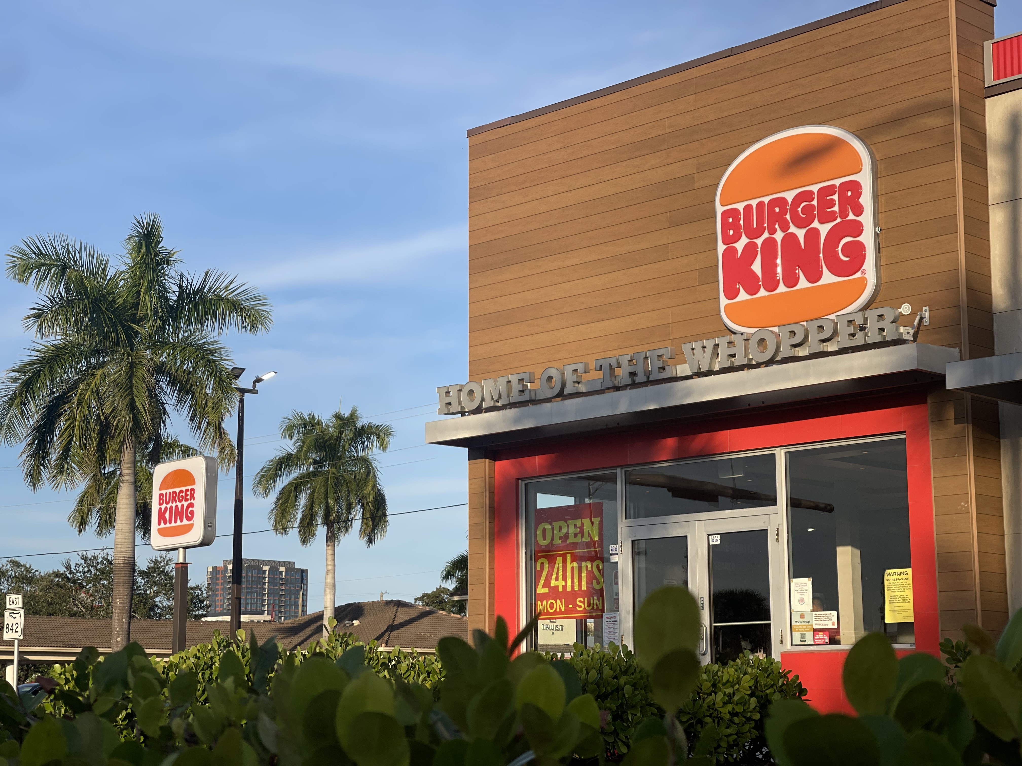 A Burger King store is surrounded by palm trees and South Florida shrubs