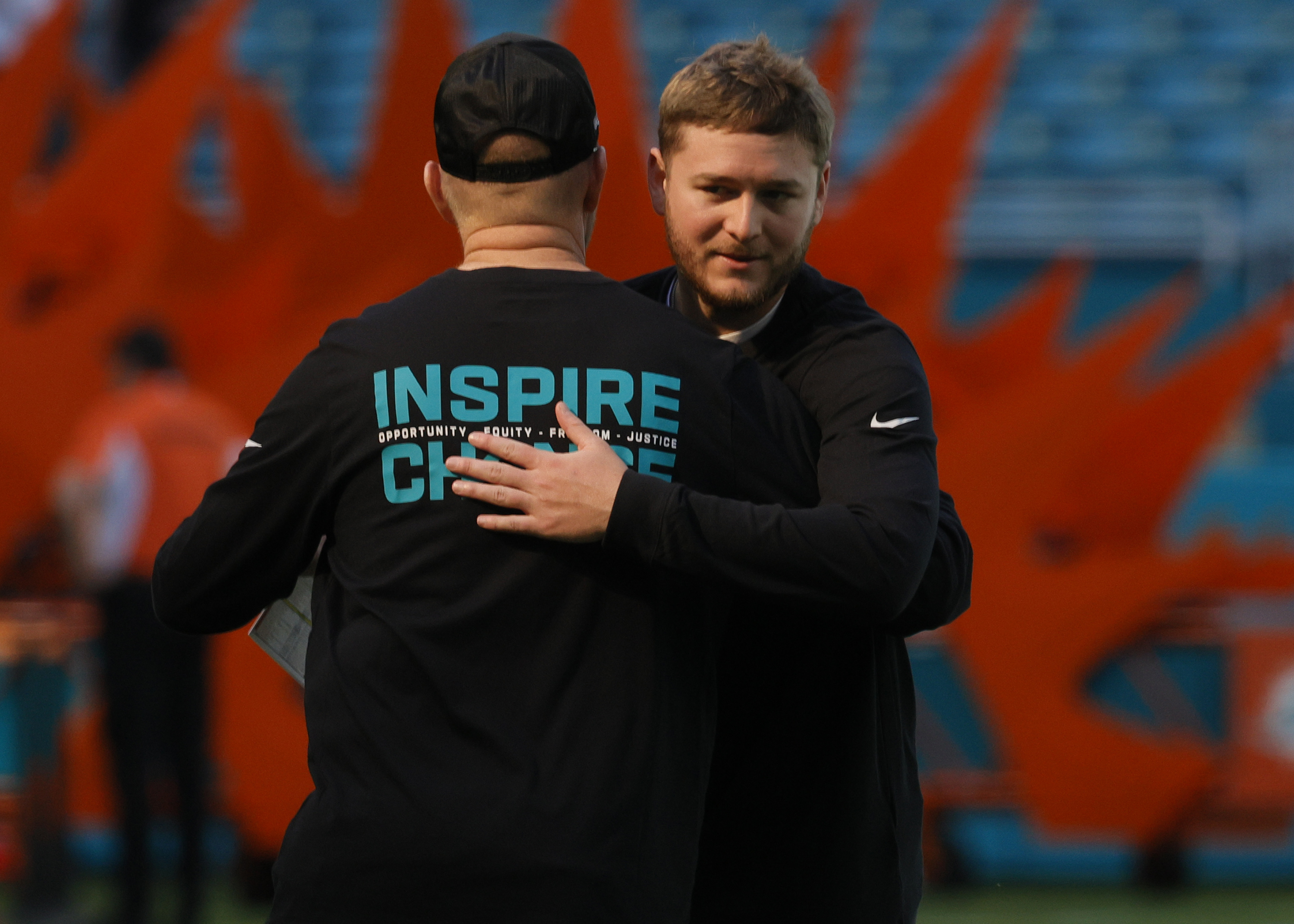 /\Miami Dolphins quarterback Quinn Ewers (14) embraces quarterback coach Darrell...