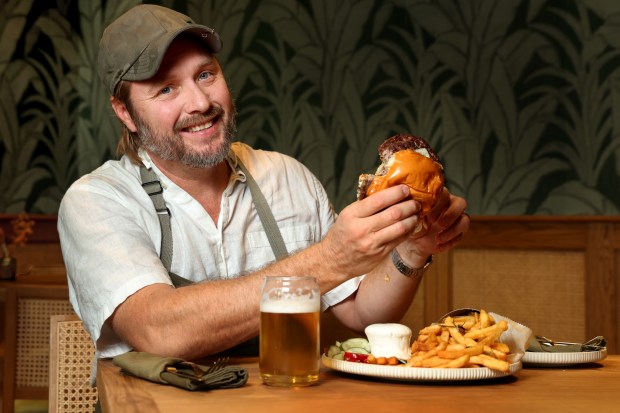 Celebrity chef Jeff McInnis with his 11-ounce Double Smash Burger, featuring a double patty, short rib and brisket blend, white American cheese, iceberg lettuce, special sauce, onions, pickles and tallow french fries, at the Florida Room restaurant at The Fort pickleball complex/recreational center in Snyder Park, Thursday, Nov. 20, 2025. (Mike Stocker/South Florida Sun Sentinel)