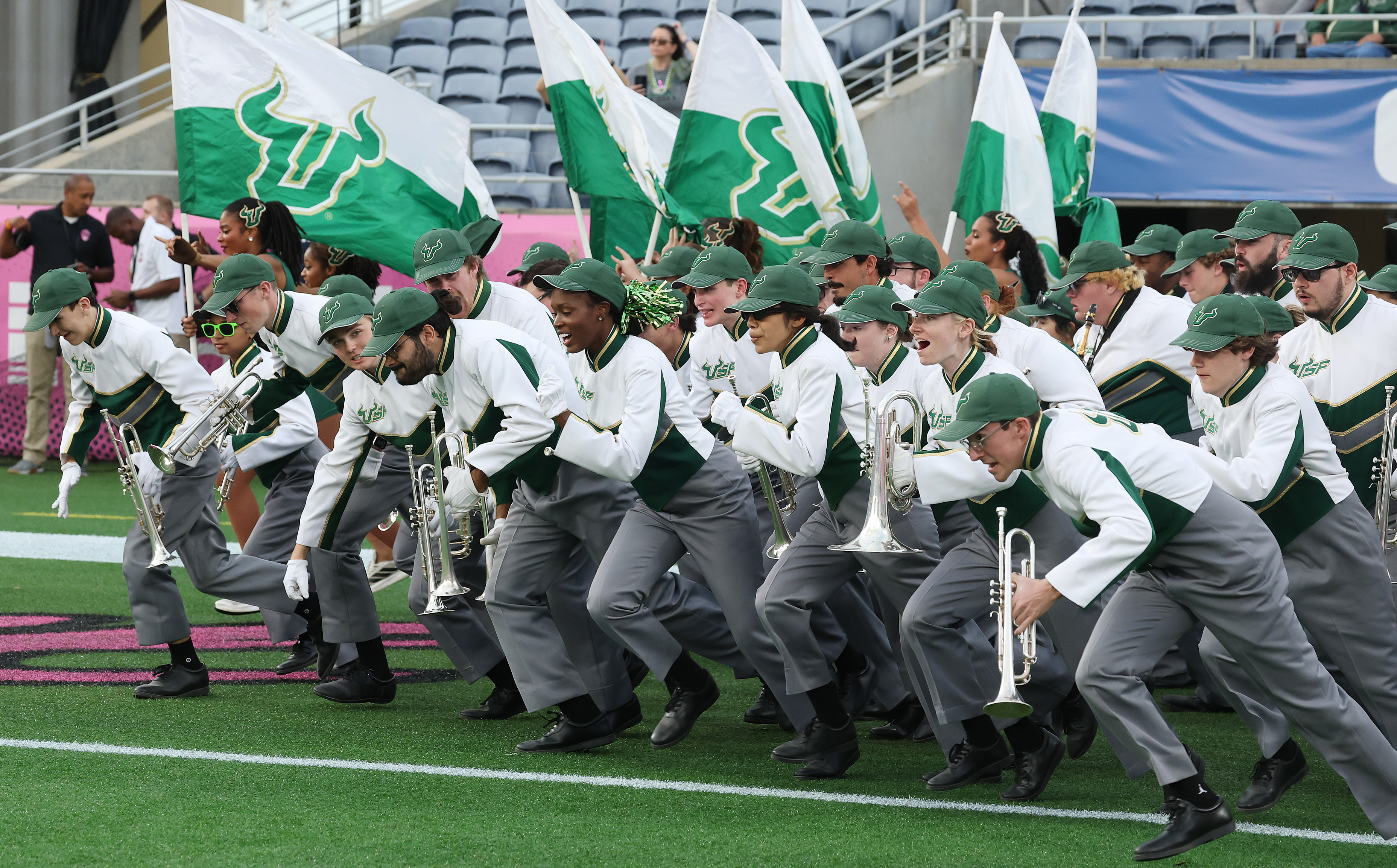 The USF band runs onto the field during the Cure...