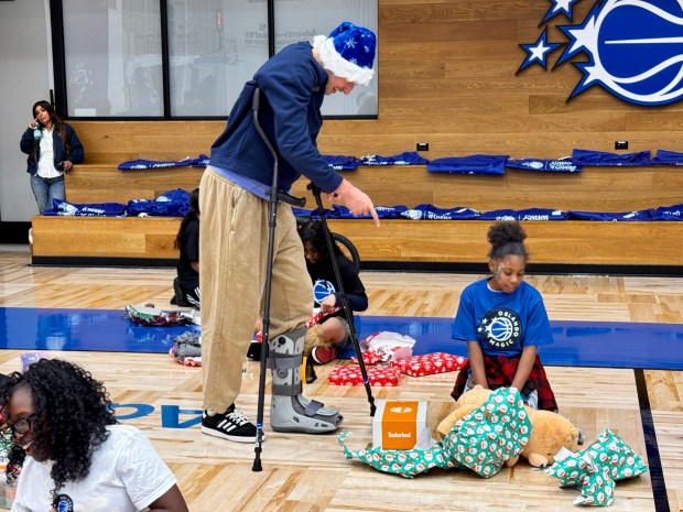 Magic forward Franz Wagner, in a boot and crutches because of a left high ankle sprain, talks with a young girl from the New Image Youth Center in Parramore as she opens up presents during a special holiday event at the AdventHealth Training Center on Wednesday night. (Jason Beede/Orlando Sentinel)