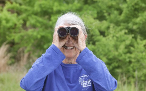 Deborah Green, president of Orange Audubon Society, peers at birds near the entrance to the Lake Apopka Wildlife Drive on Lust Road in Apopka, Friday, March 22, 2024. She is leading Audubon's fund-raising effort to build a nature center at the 70-acre birding park adjacent to the entrance of the wildlife drive. (Joe Burbank/Orlando Sentinel)