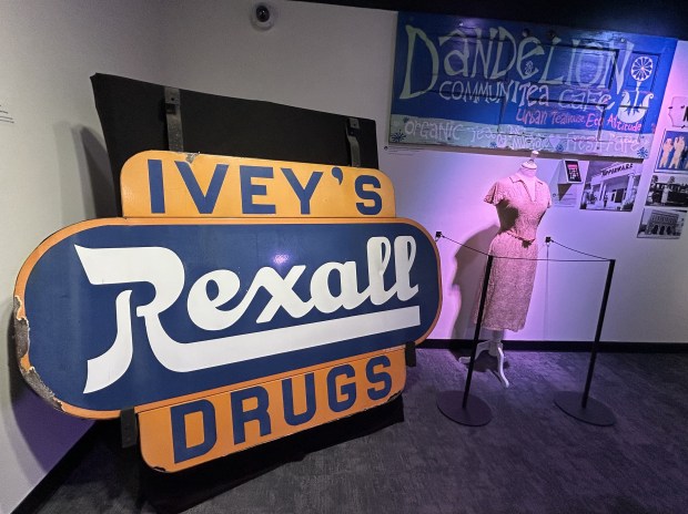Items displayed in "Orlando Collected," an exhibit created by Orange County Regional History Center as part of the celebration of the 100th anniversary of the incorporation of the city of Orlando. Pictured: Signs from Ivey's Drug Store and Dandelion CommuniTea Cafe in front of a dress that belonged to Brownie Wise, the woman who revolutionized Tupperware sales techniques. (Dewayne Bevil/Orlando Sentinel)
