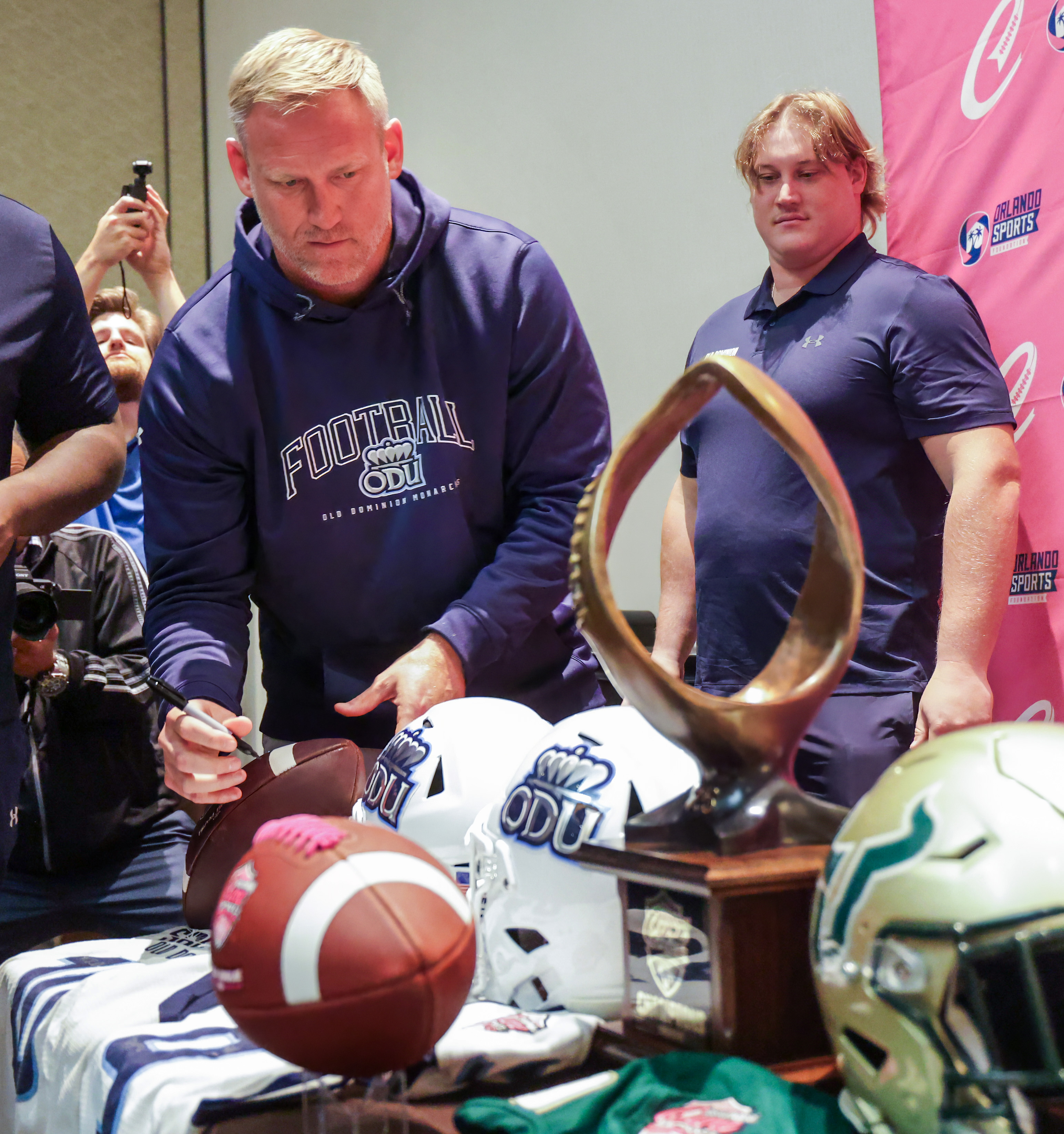 Head coach Ricky Rahne of Old Dominion signs helmets, with...
