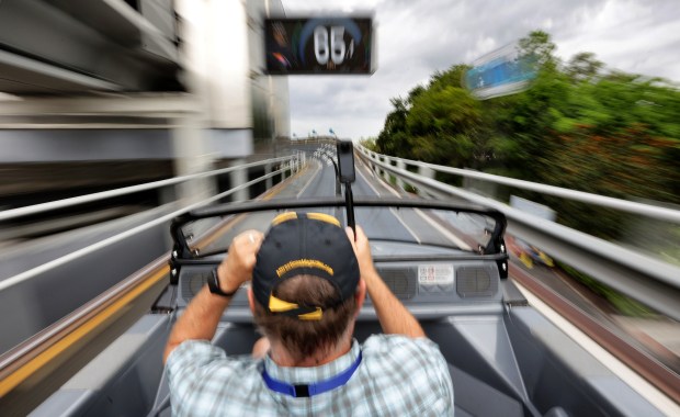 A guest holds on to his hat during a high-speed spin hitting 65 mph on the renovated Test Track attraction during a preview at Epcot, Monday, June 30, 2025. The reimagined thrill ride at Walt Disney World, sponsored by General Motors, closed for an extensive overhaul in June 2024 and will officially reopen to Epcot guests on July 22. (Joe Burbank/Orlando Sentinel)