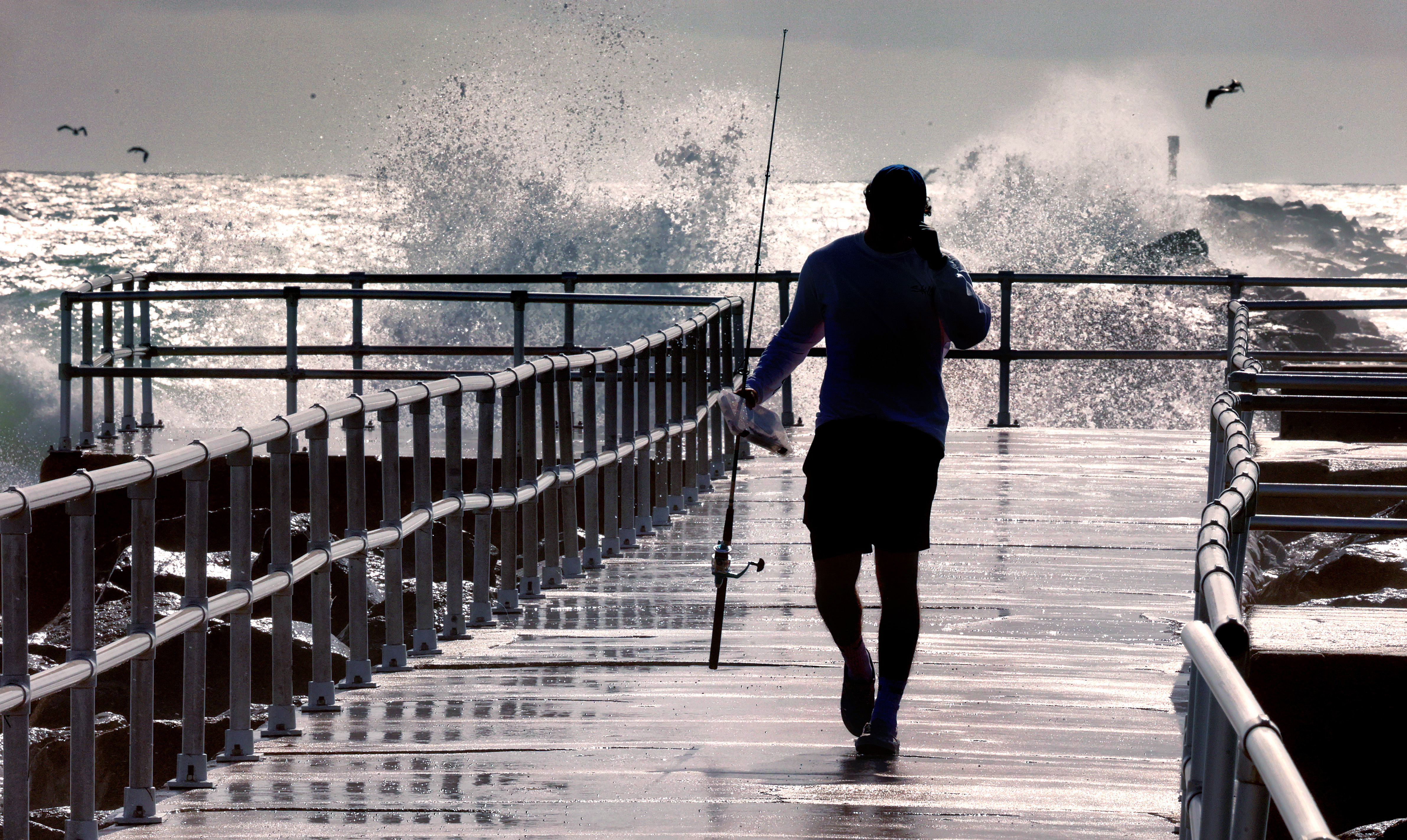 A fisherman braves 9-foot waves generated by Hurricane Erin crashing...
