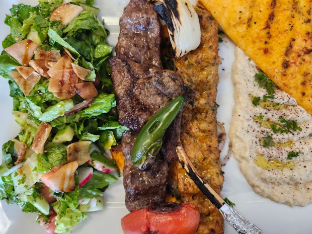 The Hala Grill platter from Rawsha Mediterranean cuisine features a lamb chop, chicken kofta and Iraqi kebab and two sides, in this case, fatough and babaganoush. (Amy Drew Thompson/Orlando Sentinel)