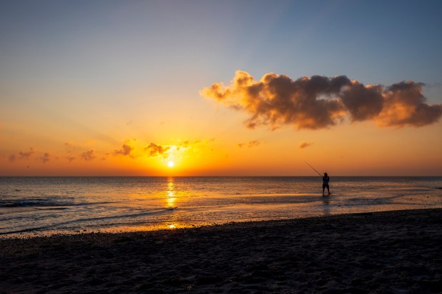 A fisherman is silhouetted as the sun rises over the Atlantic Ocean on New Year's Day as seen from Hangar's Beach across from Patrick Space Force Base on Jan. 1. (Patrick Connolly/Orlando Sentinel)