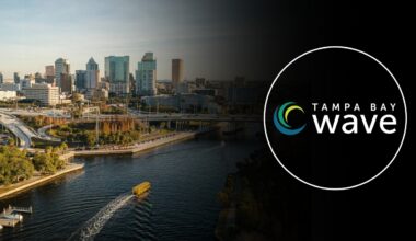 Aerial view of downtown Tampa along the Hillsborough River with the Tampa Bay Wave logo overlaid.