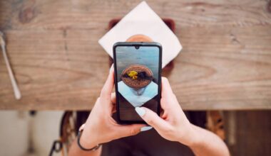 A person photographs a plated dessert with a smartphone at a café table, illustrating how food content is created for social media.