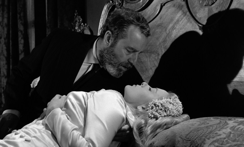 black-and-white film still of a man and woman gazing into each other's eyes in bed