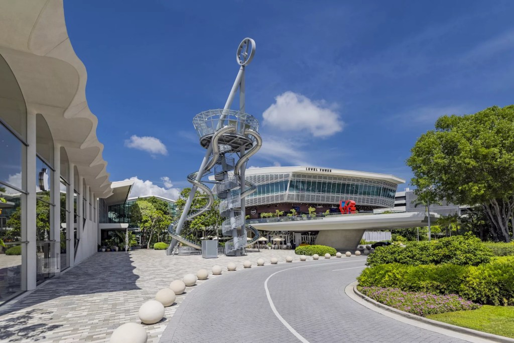 photo of the street entrance to a mall with a tower to the left of it