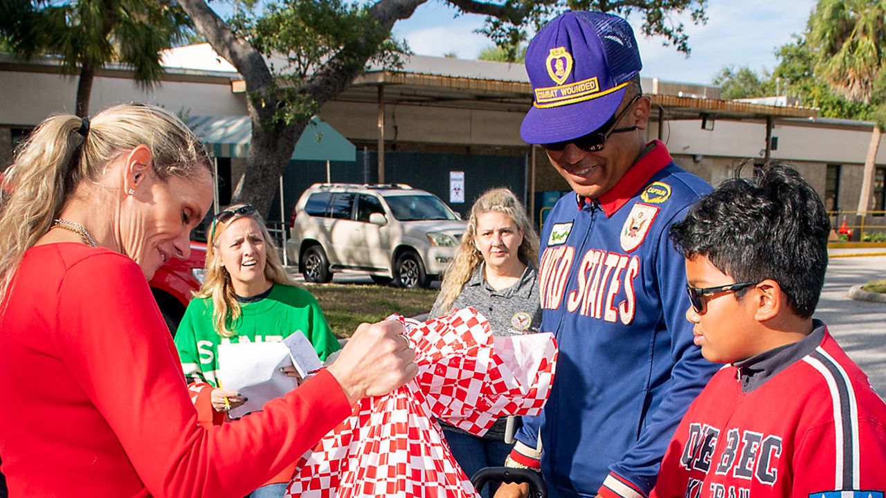 Pinellas military family serving during Season of Giving. Seen here are Christine Long, in red, and Mr. Springer’s granddaughter, handing out toys during the Bay Pines VA Adopt-a-Veteran program. (Courtesy: Bay Pines VA)
