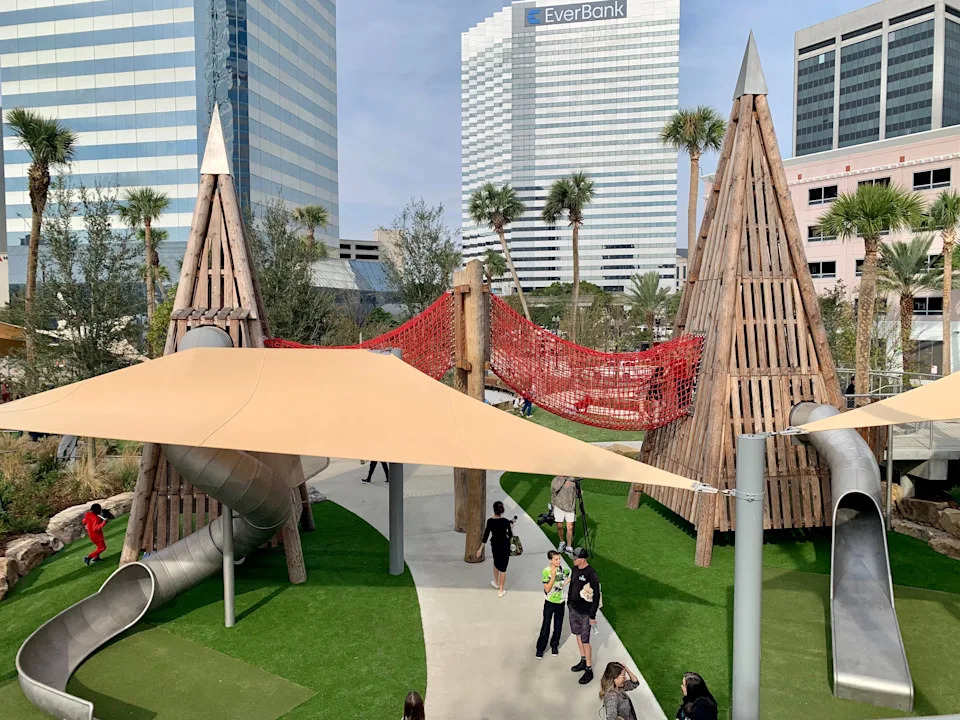 The wooden towers in the Riverside Plaza playground create their own miniature skyline against the office towers of downtown Jacksonville. The playground opened Dec. 5, 2025 as city leaders celebrated the first phase of Riverside Plaza on the former site of the Jacksonville Landing.