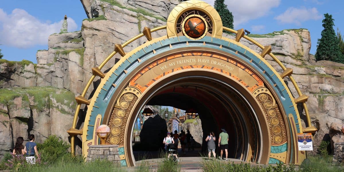 A large, ornate archway with a golden and bronze design marks the entrance to the Epic Universe theme park area.