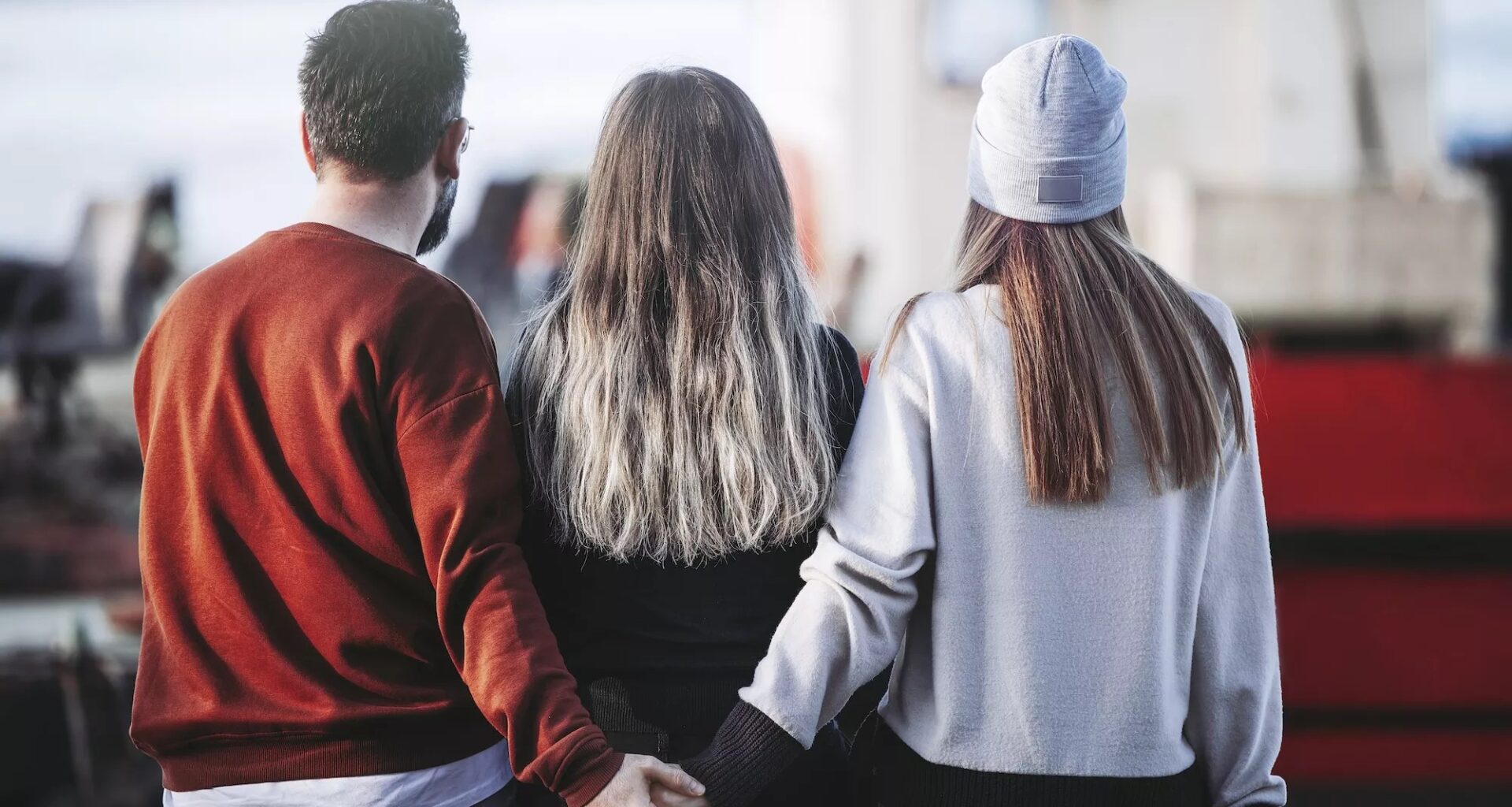 photo of a man and woman holding hands behind another woman
