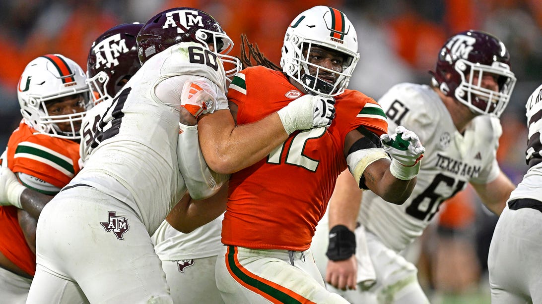 MIAMI GARDENS, FL - SEPTEMBER 09: Miami defensive lineman Jahfari Harvey (12) is held by Texas A&M offensive lineman Trey Zuhn (60) while pursuing the ball carrier in the fourth quarter as the Miami Hurricanes faced the Texas A&M Aggies on September 9, 2023, at Hard Rock Stadium in Miami Gardens, Florida.