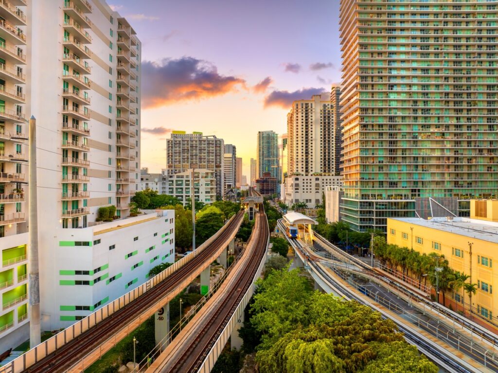 Railroad tracks and public train line run through the heart of Miami Brickell downtown in Florida, USA, surrounded by sunset lit skyscrapers of the financial district