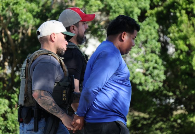 Law enforcement personnel detain a man during an ICE operation on Griffin Road in Davie, Wednesday, Dec. 10, 2025. Residents report that the agency has been working in the area beginning Sunday. (Joe Cavaretta/South Florida Sun Sentinel)