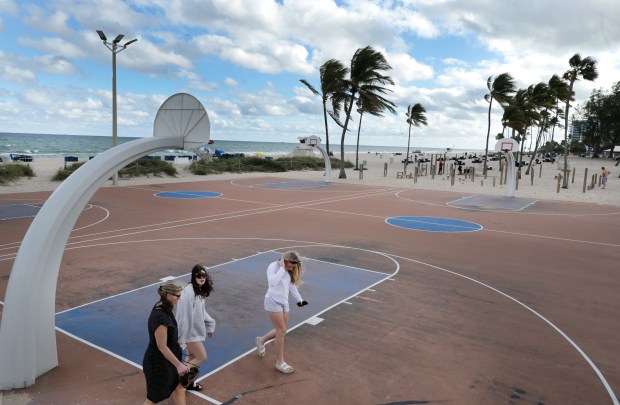 Three women walk by the basketball courts on Fort Lauderdale beach on Tuesday. (Carline Jean/South Florida Sun Sentinel)