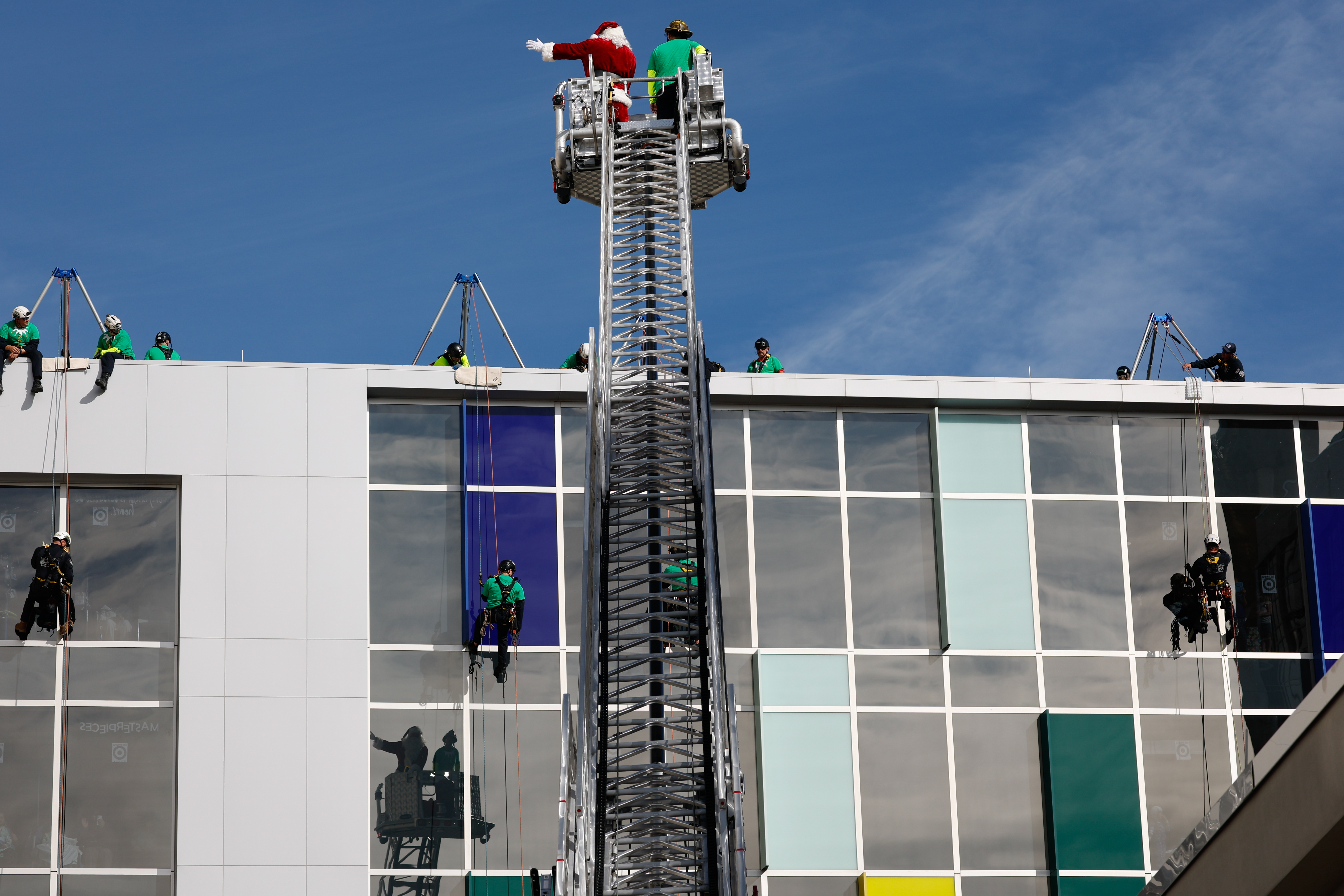Santa gives a wave from high above in a ladder truck as Orange County Fire Rescue and the Orlando Fire Department rappel down the side of AdventHealth for Children, interacting with children and their families through the windows on Thursday, December 18, 2025.(Rich Pope/Orlando Sentinel)
