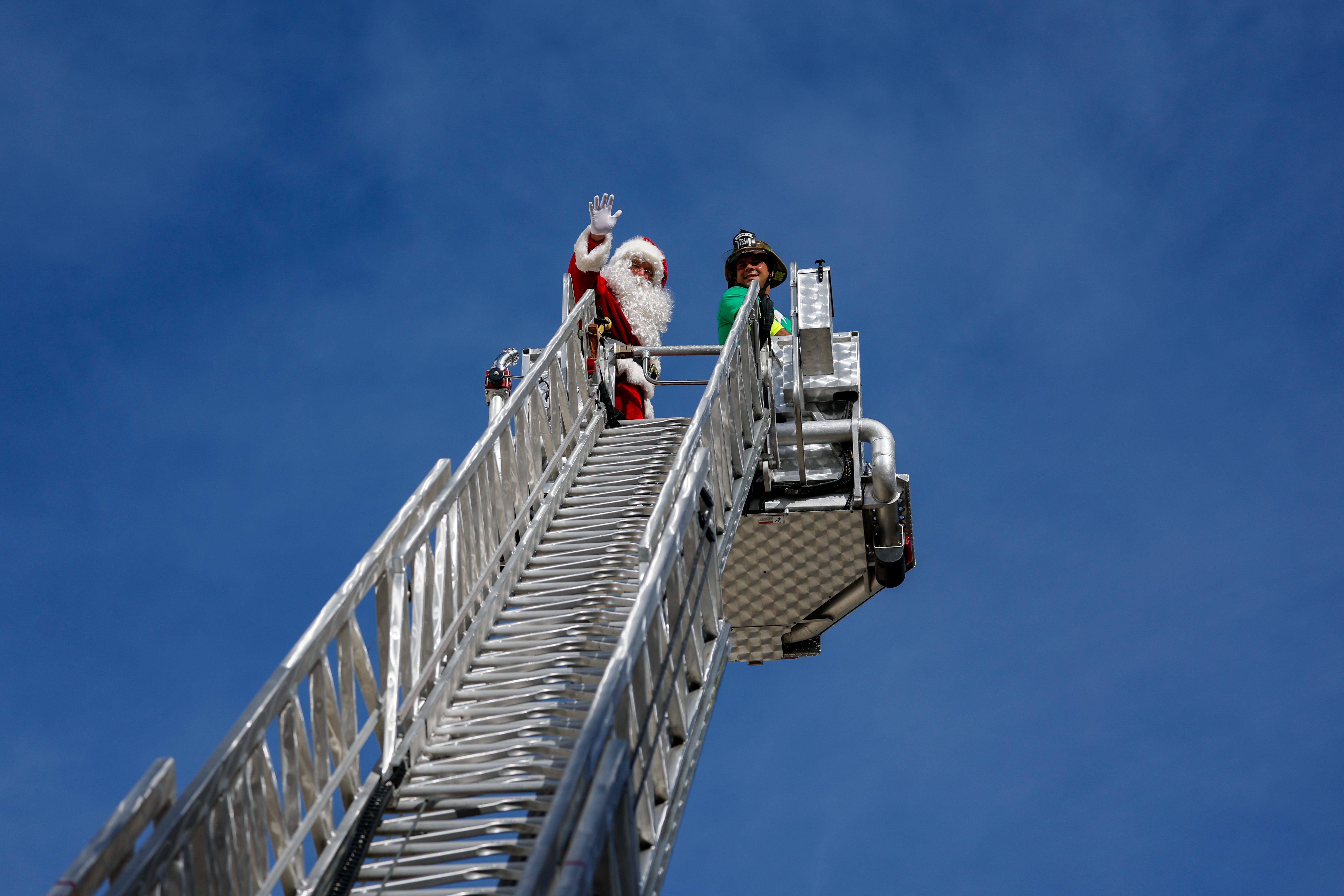 Santa gives a wave from high above in a ladder truck as Orange County Fire Rescue and the Orlando Fire Department rappel down the side of AdventHealth for Children, interacting with children and their families through the windows on Thursday, December 18, 2025.(Rich Pope/Orlando Sentinel)