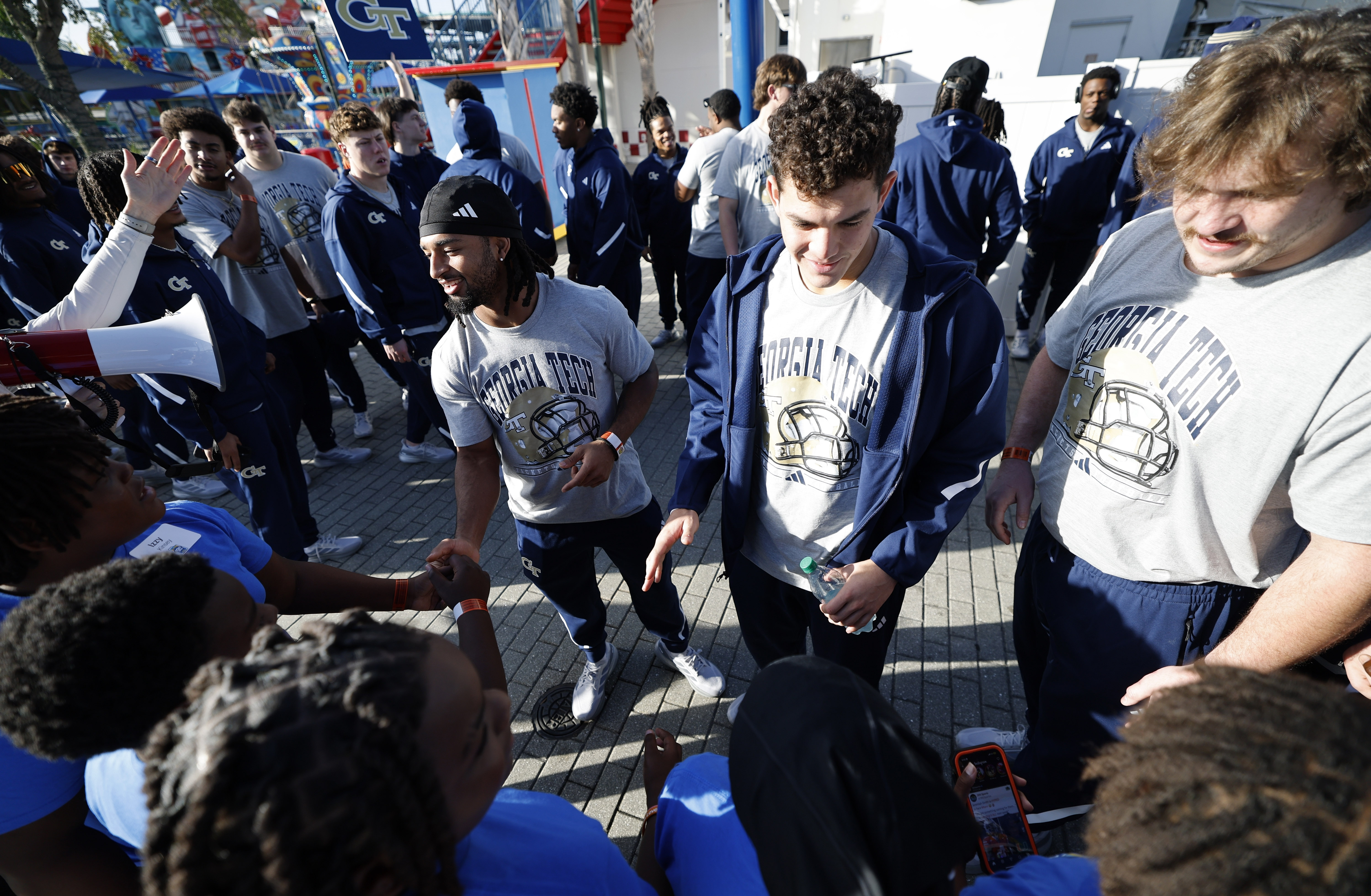 Georgia Tech players high-five kids as they arrive for a...