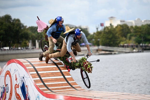 Members of the Born to Thrive Coaster team from Orlando, Fla., crash, while competing in the Red Bull Tandem Rollercoaster event at Cranes Roost Park, Saturday, Sept. 27, 2025, in Altamonte Springs, Fla. Thirty teams, chosen from more than 300 applications, competed on custom, rollercoaster-themed tandem bicycles across a 300-foot obstacle course over water with drops as high as six feet. Teams were judged on creativity, showmanship and distance. (Phelan M. Ebenhack for the Orlando Sentinel)