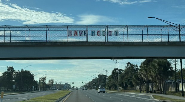 A homemade "Save McCoy"sign hangs on a pedestrian bridge over South Semoran Blvd near McCoy Elementary School on Saturday, December 13, 2025. McCoy is one of seven schools the district plans to close starting in the 2026-27 school year because of declining enrollment. (Ryan Gillespie/Orlando Sentinel)
