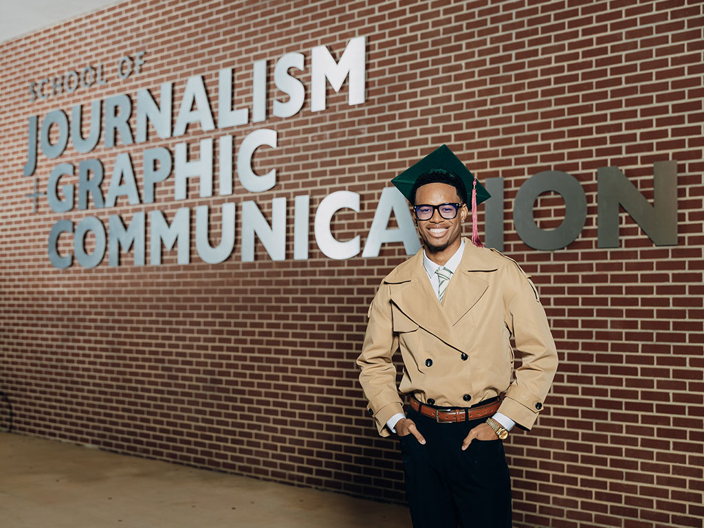 Florida A&M University graduate Joel Mitchell stands outside the School of Journalism & Graphic Communication, marking the completion of his academic journey.