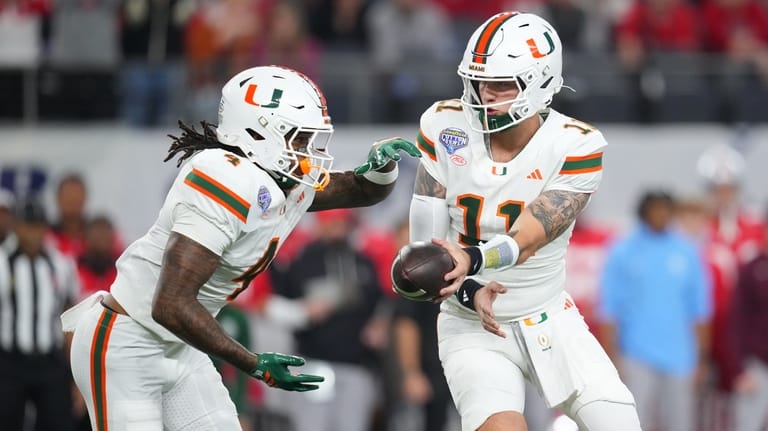 Miami quarterback Carson Beck, right, prepares to hand off to...