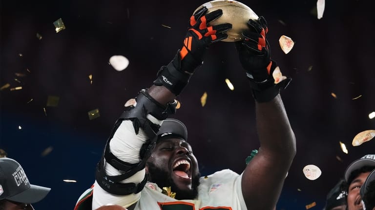 Miami offensive lineman Markel Bell holds up a trophy after...