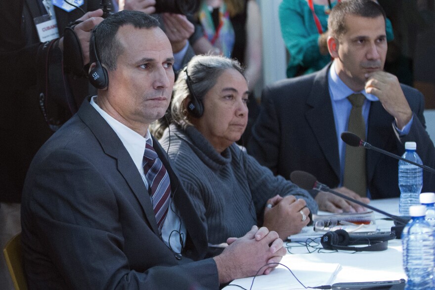 Three people sit at a table with headsets