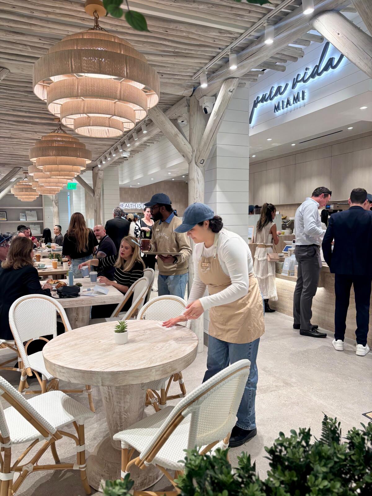 An employee clears a table for the next round of customers at Pura Vida Miami at South Coast Plaza in Costa Mesa.