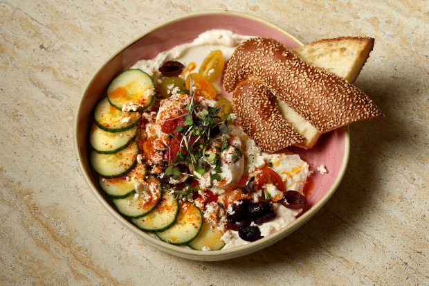 An Israeli breakfast featuring two eggs, avocado, feta, halloumi, tomato, Kalamata olives, and Turkish yogurt is served with a Jerusalem bagel at Cafe Bastille, Thursday, Jan. 15, 2026. (Mike Stocker/South Florida Sun Sentinel)