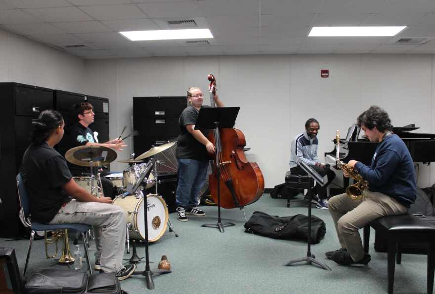 Bass player Gabe Burgos plays upright as Diego Figueredo (left), Nicholas Romig (drums), Brandon Robertson (piano) and Jonathan Esyaman (saxophone) look on.