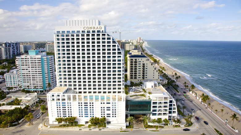 White, sleek oceanfront high-rise hotel across the street from beach.