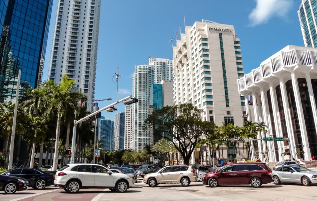 image shows busy traffic and sky scrapers on a sunny day in downtown miami