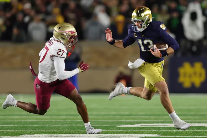 SOUTH BEND, INDIANA - NOVEMBER 09: Riley Leonard #13 of the Notre Dame Fighting Irish stiff arms Ashlynd Barker #27 of the Florida State Seminoles during the first half at Notre Dame Stadium on November 09, 2024 in South Bend, Indiana. (Photo by Michael Reaves/Getty Images)
