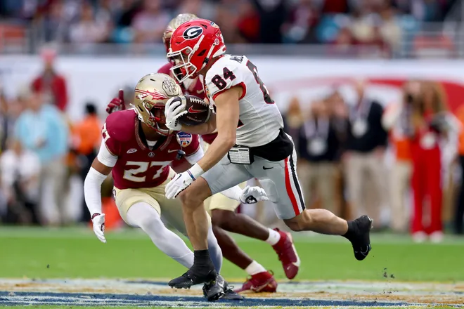MIAMI GARDENS, FLORIDA - DECEMBER 30: Ladd McConkey #84 of the Georgia Bulldogs runs with the ball while being chased by Ashlynd Barker #27 of the Florida State Seminoles in the second quarter during the Capital One Orange Bowl at Hard Rock Stadium on December 30, 2023 in Miami Gardens, Florida. (Photo by Megan Briggs/Getty Images)
