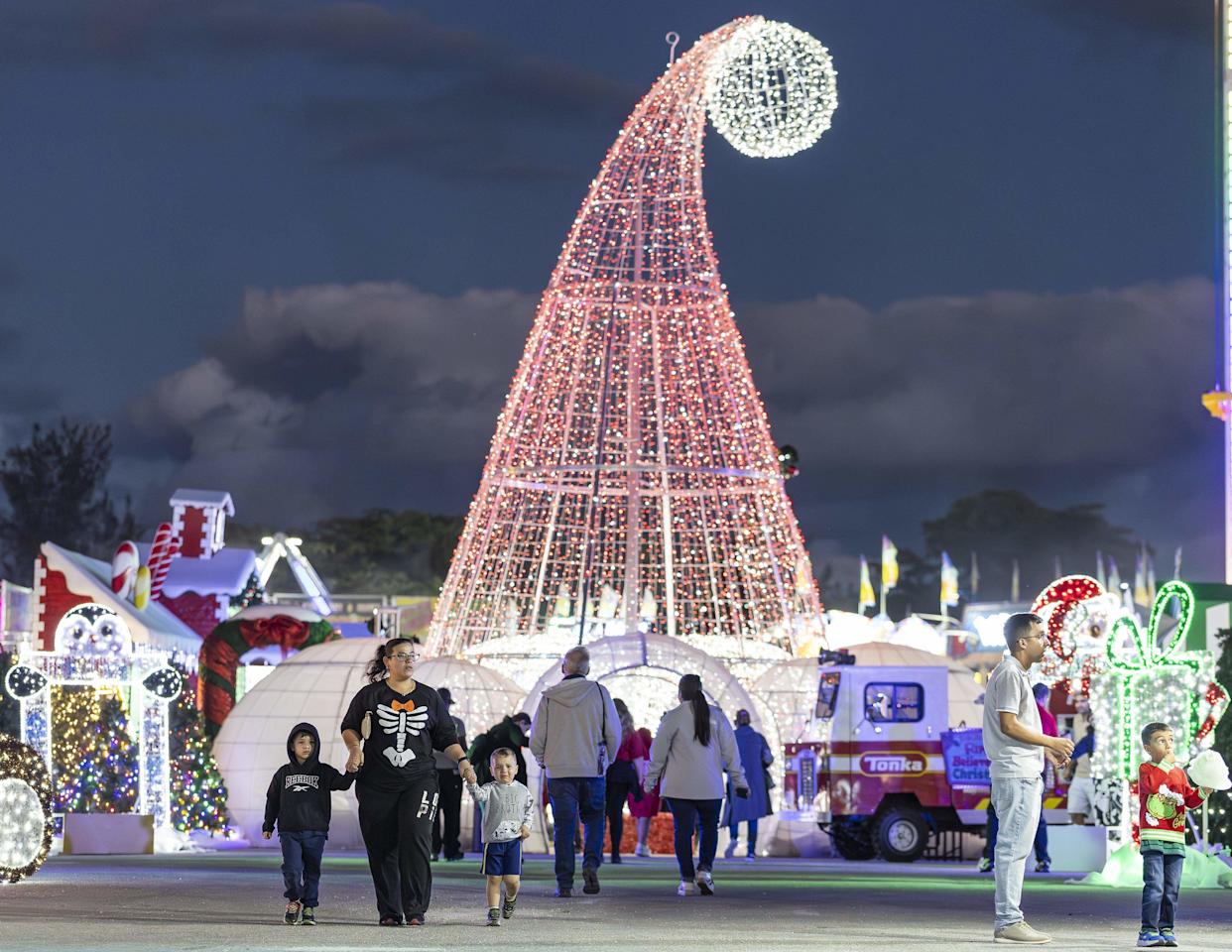 From left to right: Nathan Crespo, 4, Natalie Rodriguez, 29, and Logan Garcia, 2, hold hands during the grand opening of Ripley's Believe It or Not! Christmas Park at Amelia Earhart Park on Thursday, Nov. 13, 2025, in Hialeah, Fla.