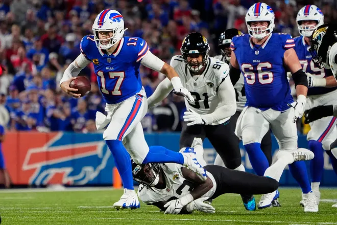 Sep 23, 2024; Orchard Park, New York, USA; Buffalo Bills quarterback Josh Allen (17) breaks a tackle by Jacksonville Jaguars linebacker Devin Lloyd (33) during the first half at Highmark Stadium. Mandatory Credit: Gregory Fisher-Imagn Images