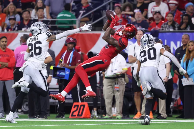 Dec 21, 2025; Houston, Texas, USA; Houston Texans wide receiver Nico Collins (12) makes a recption as Las Vegas Raiders cornerback Darien Porter (26) and safety Isaiah Pola-Mao (20) defend during the fourth quarter at NRG Stadium. Mandatory Credit: Troy Taormina-Imagn Images