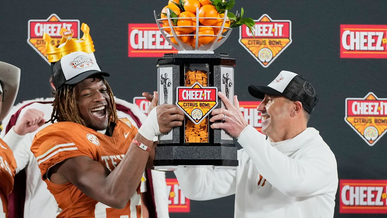 Texas linebacker Ty'Anthony Smith, left, and head coach Steve Sarkisian hold up the championship trophy after defeating Michigan in the Citrus Bowl NCAA college football game, Wednesday, Dec. 31, 2025, in Orlando, Fla. (AP Photo/John Raoux)