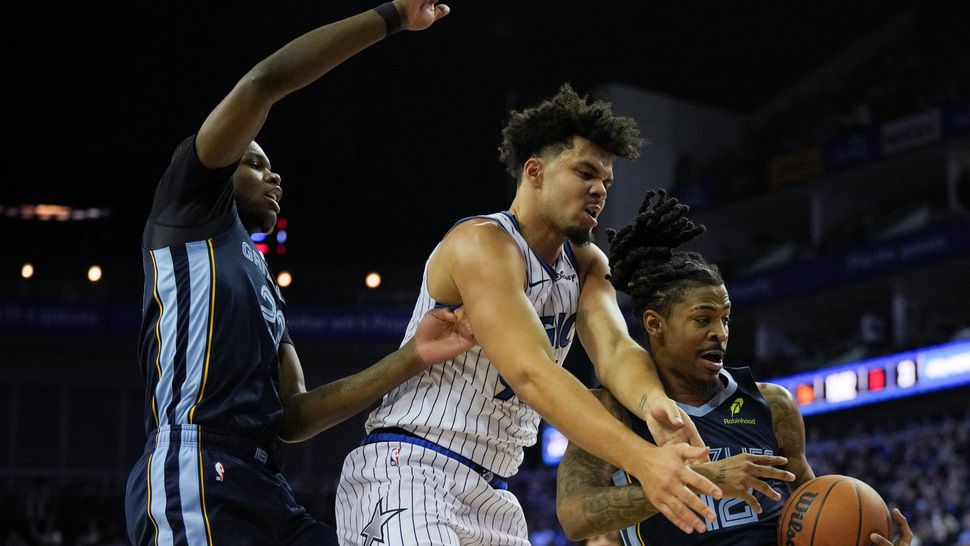 Orlando Magic forward Noah Penda, center, Memphis Grizzlies forward Cedric Coward, left and Memphis Grizzlies guard Ja Morant, right, fight for the ball during the first half of an NBA basketball game Sunday, Jan. 18, 2026, in London. (AP Photo/Kin Cheung)