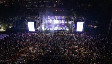 Photo of a stage at a festival at night and a lot of people in the crowd