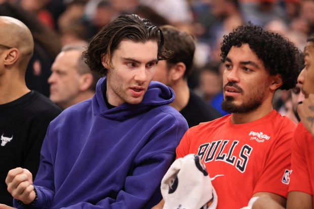 Bulls guard Josh Giddey, left, sits on the bench in street clothes in the first quarter against the Magic at the United Center on Jan. 2, 2026, in Chicago. (John J. Kim/Chicago Tribune)