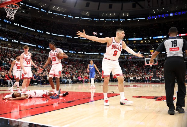 Bulls center Nikola Vučević (9) argues a foul call on forward Isaac Okoro, on floor, with an official in the fourth quarter against the Magic at the United Center on Jan. 2, 2026, in Chicago. (John J. Kim/Chicago Tribune)