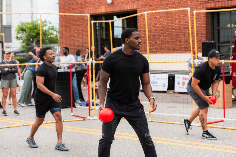 Three teammates holding red dodgeballs and looking focused during an outdoor tournament game.